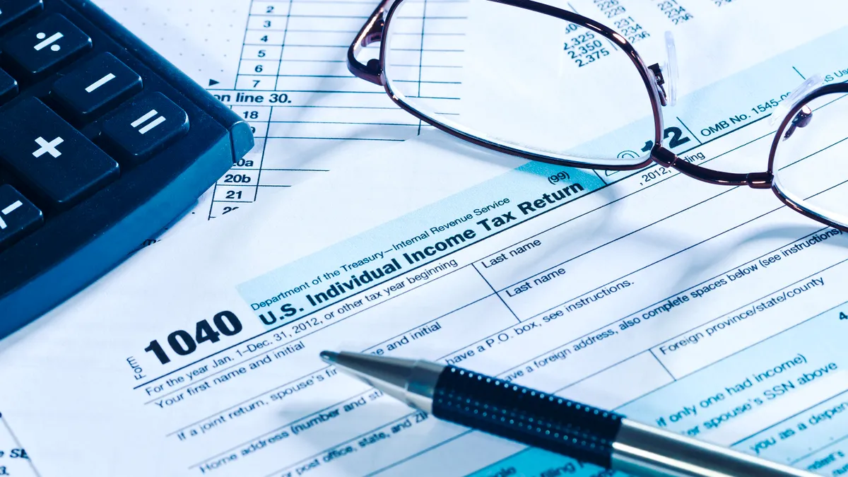 American tax forms with a calculator, reading glasses and a pen