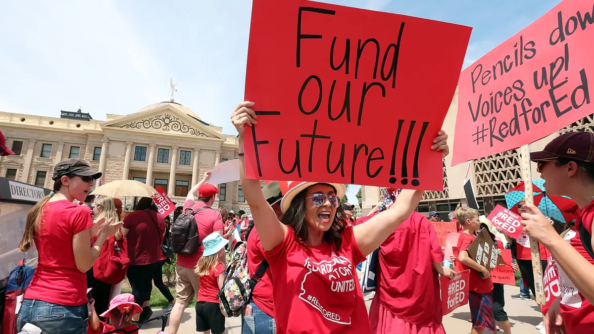 An Arizona teacher holds up a sign in front of the State Capitol during a #REDforED rally on April 26, 2018 in Phoenix, Arizona.