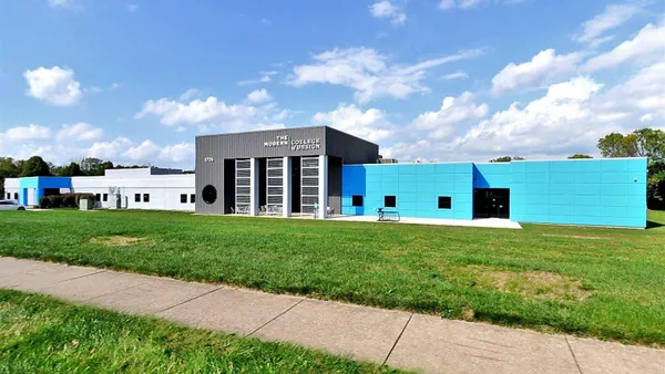 The Modern College of Design's main campus building with turquoise and gray siding, with a sidewalk in front of it.