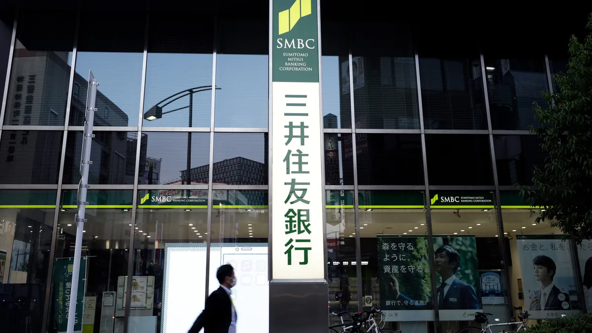 A vertical SMBC sign stands outside a glass office building.