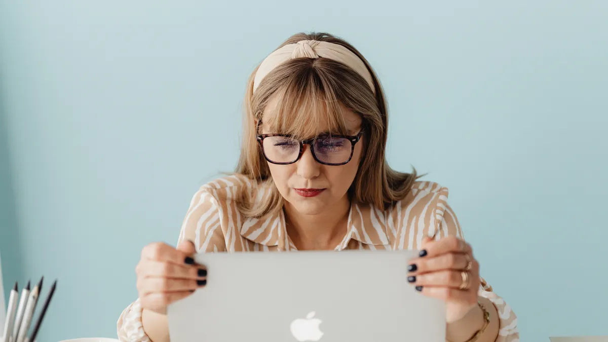 A women looks in frustration at her laptop screen.