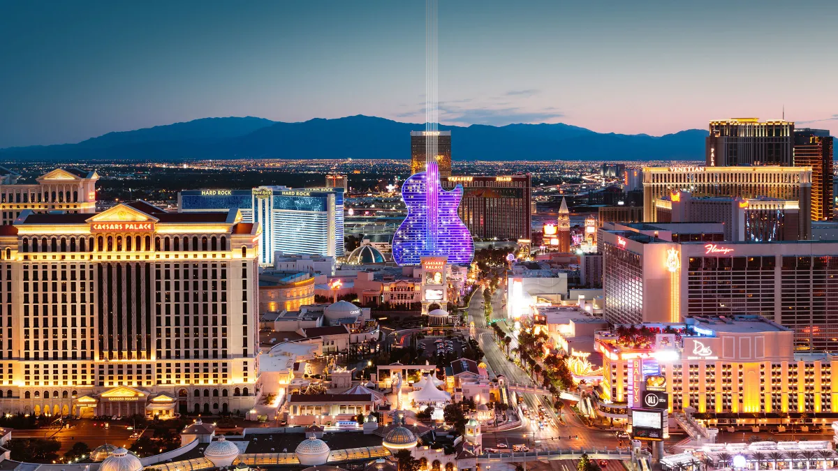 A guitar-shaped building is lit up in purple on the Strip.