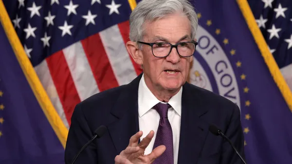 The Fed's chairman, Jerome Powell, speaks at a news conference in front of an American flag.