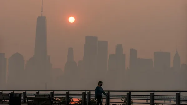 A woman walks in front of NYC skyline.