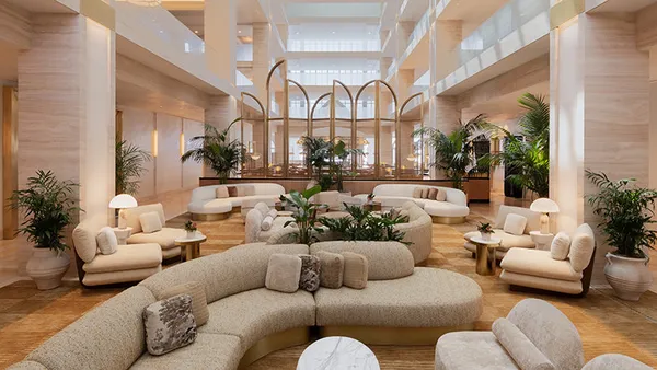 Beige-colored couches in a high-ceilinged lobby.