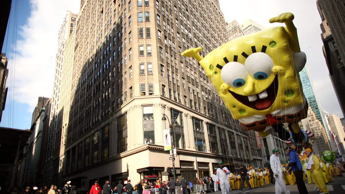 A large balloon of cartoon character SpongeBob SquarePants floats over people on a street