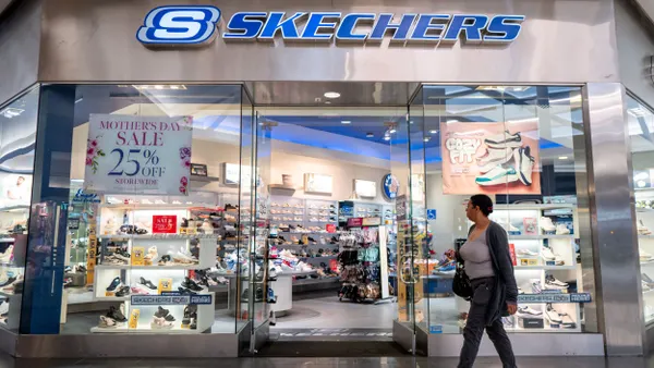 A person walks in front of a Skechers store in a mall.