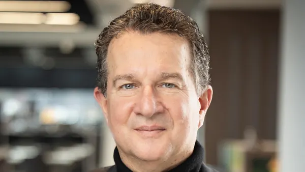 John Owen, Blaze Pizza's new CEO, glowers at a camera. He is a white man in a black turtleneck and dark suit coat.