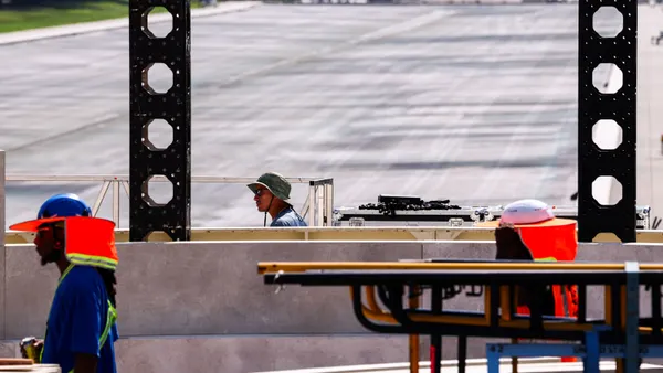 Construction workers in gear next to various construction materials.