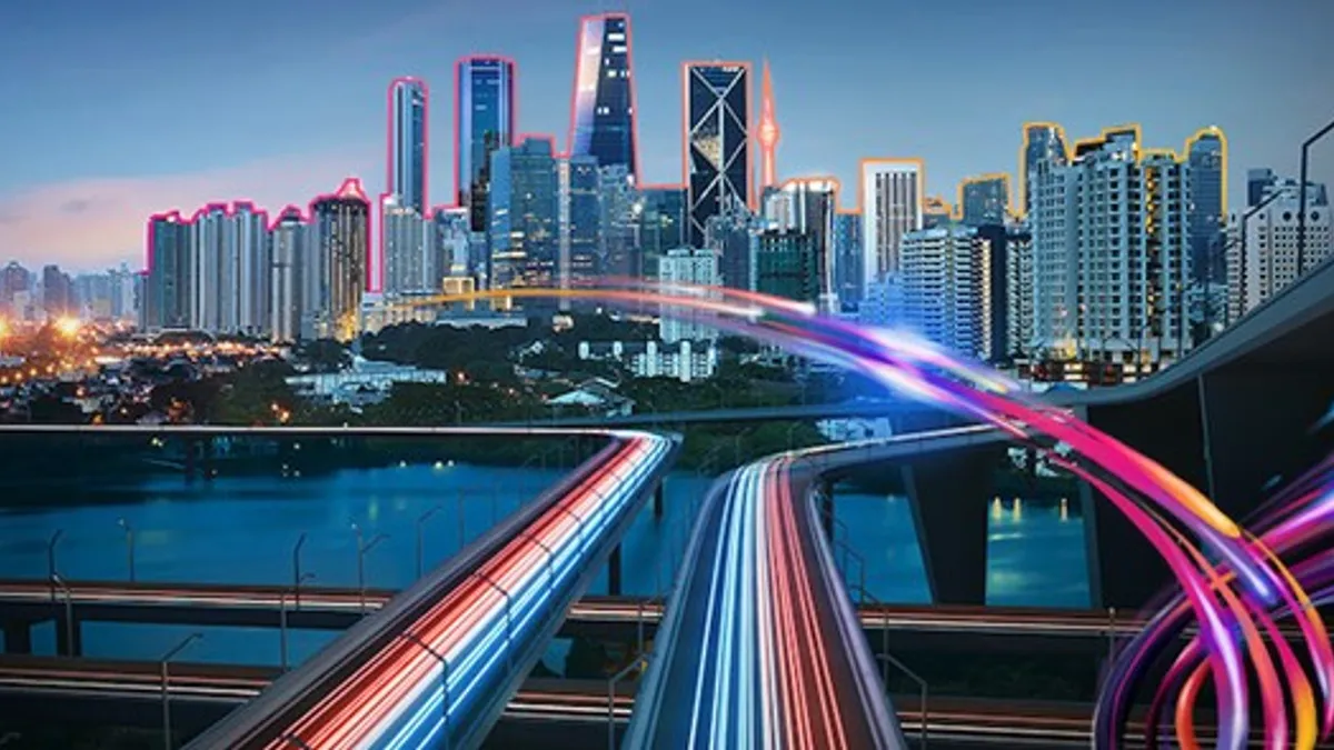 Highway with vehicle light trails leading to modern illuminated night modern cityscape