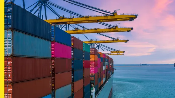 Colorful shipping crates onboard a vessel on the ocean with pink and blue sunset.