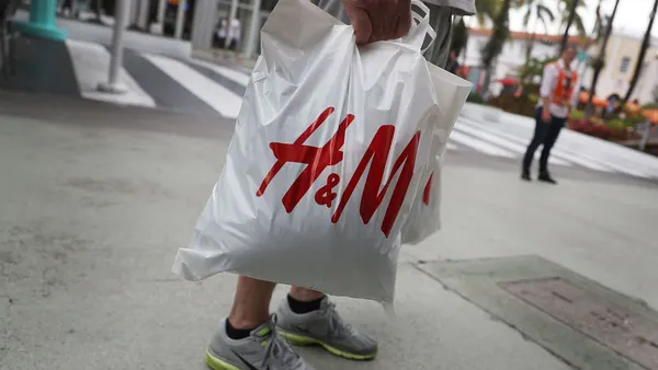 A person seen carrying a white bag with an H&M logo on it.