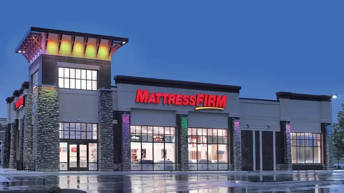 An illuminated Mattress Firm storefront at night.