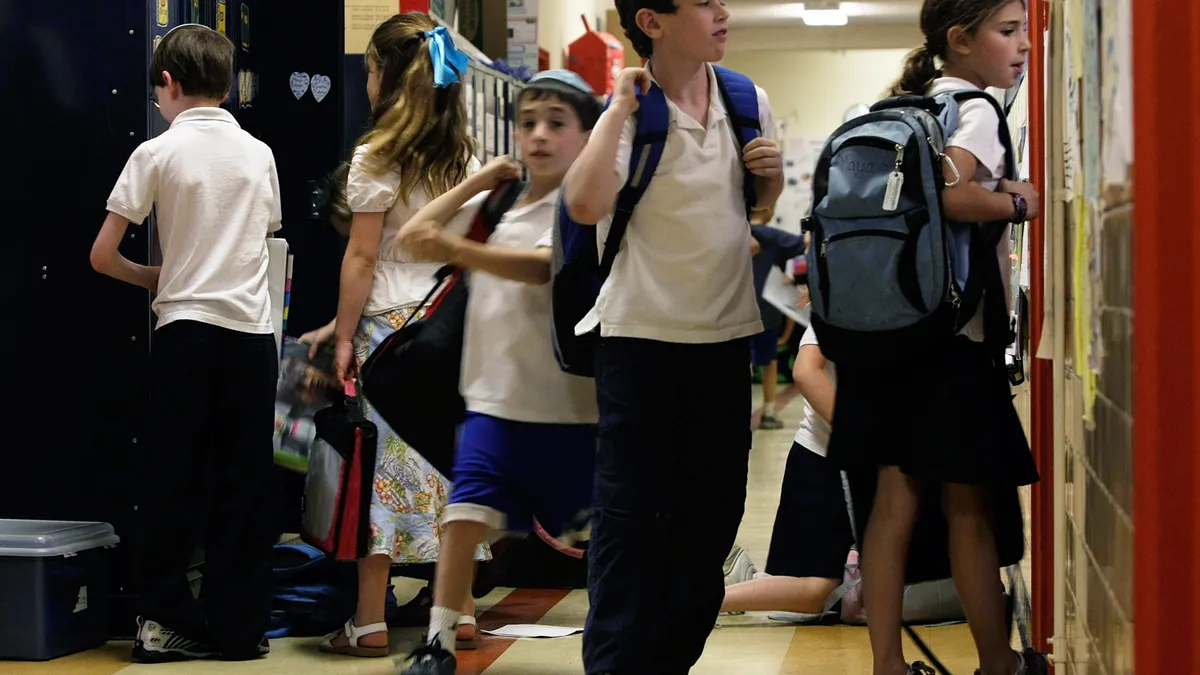 A student wearing Jewish head garb walks in a school hallway