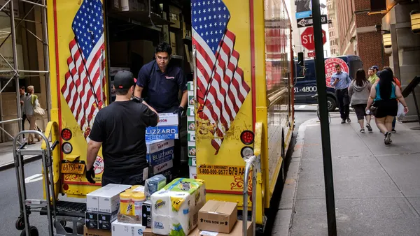 A delivery team unloads packages from the back of their truck.