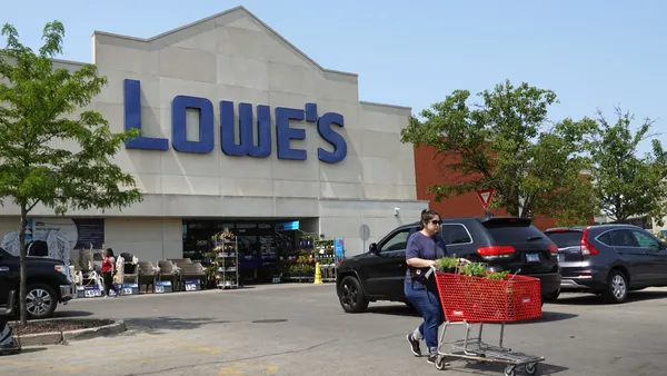 A customer pushes a cart outside a Lowe's store.