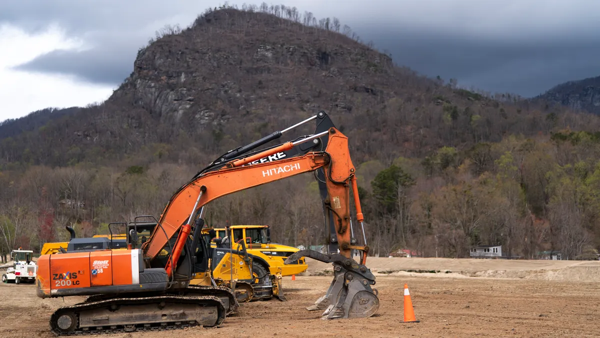 Heavy machinery sits near the Broad River in a landscape scarred by Hurricane Helene