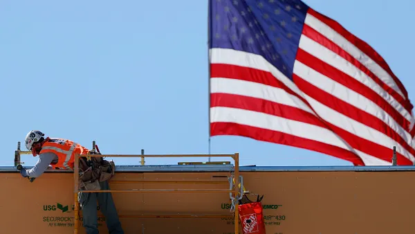 A construction worker in front of an American flag.