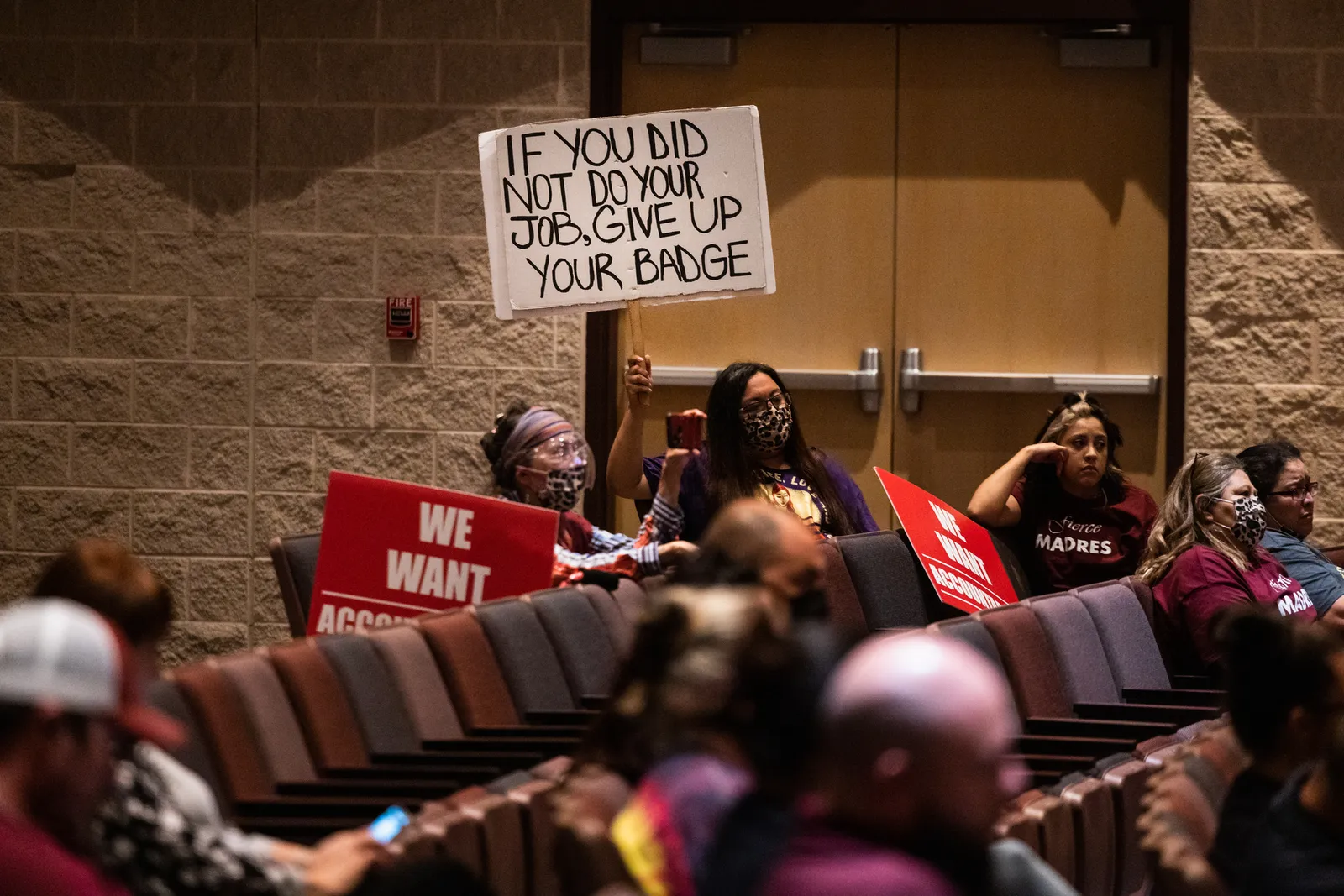 Attendees hold signs as the Uvalde Consolidated Independent School District Board holds a special meeting to consider the firing of Police Chief Pete Arredondo on August 24, 2022 in Uvalde, Texas.