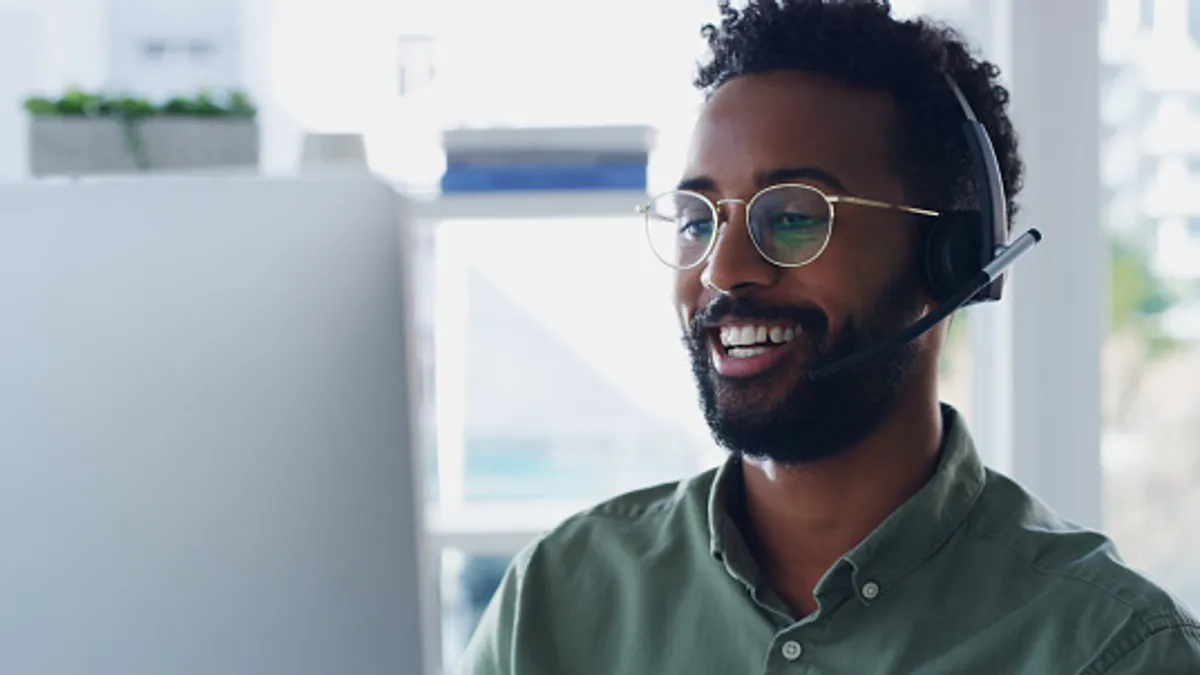 Person wearing headset while working on a computer in his office