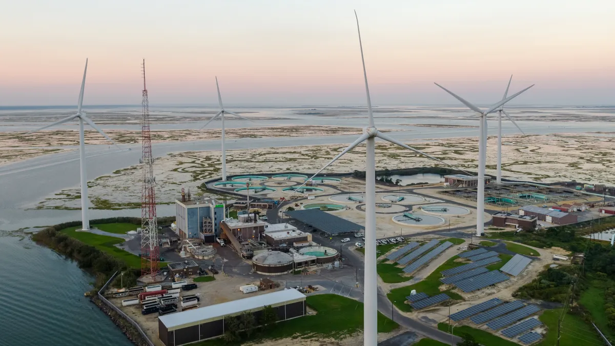 A wastewater treatment plant powered by wind turbines and solar panels near Atlantic City in New Jersey, USA. Aerial elevated view at the sunset.