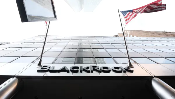 Shot of BlackRock building from below with company logo centered and U.S. flag visible to the right of company name.