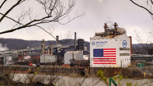 A white factory with the blue U.S. Steel logo and U.S. flag on the building.