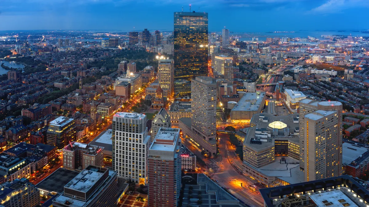 A skyshot of Boston across a dusky view with a river through the left side of the photo.