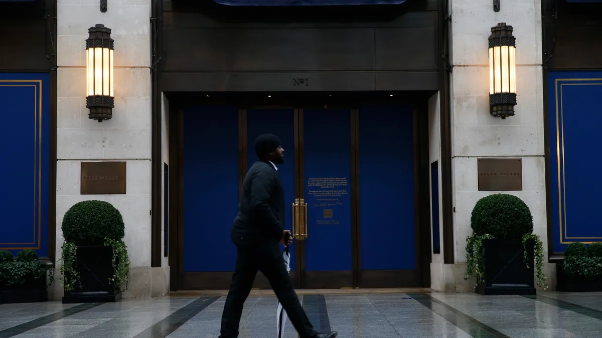 A man in a suit strolls past a closed Ralph Lauren store in the evening.