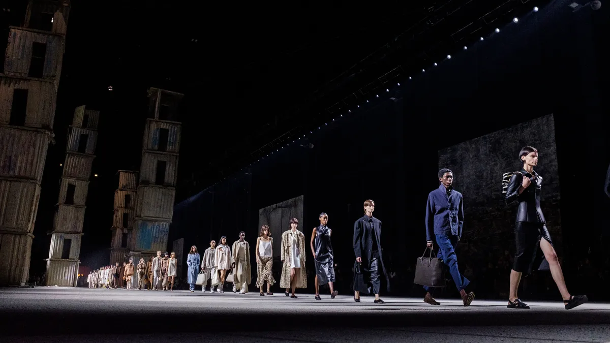 Models walk a long and dark runway during a Tod's fashion show.