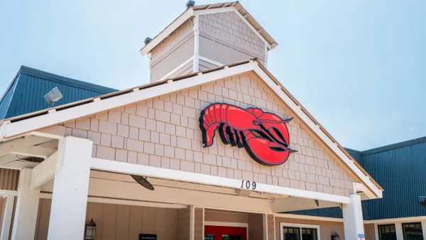 A white building with shinges and a logo of a red lobster