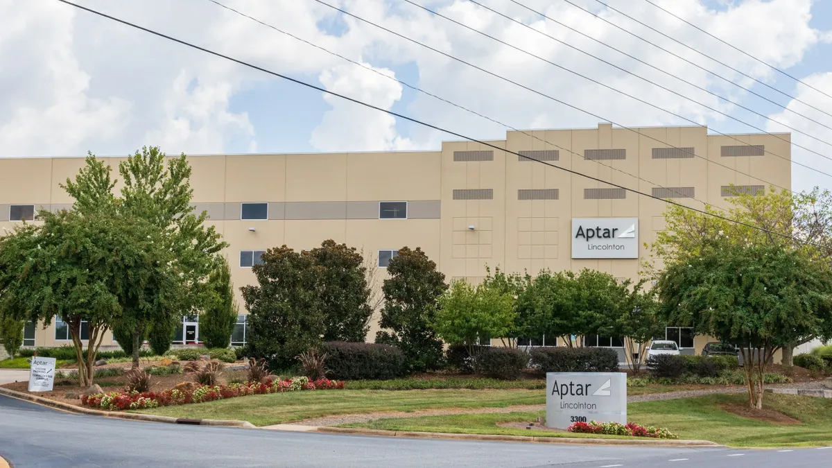 The exterior of an industrial facility with signs showing the logo for packaging company Aptar.