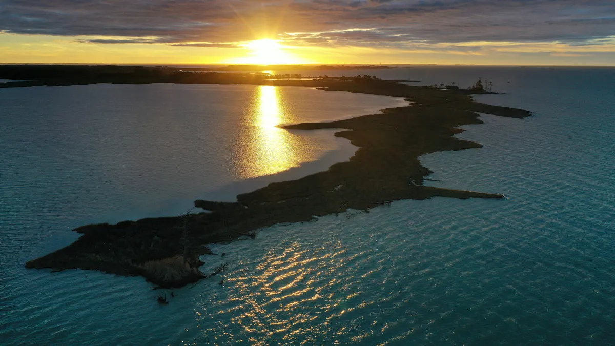 Aerial view of a thin strip of land jutting into an expanse of water.