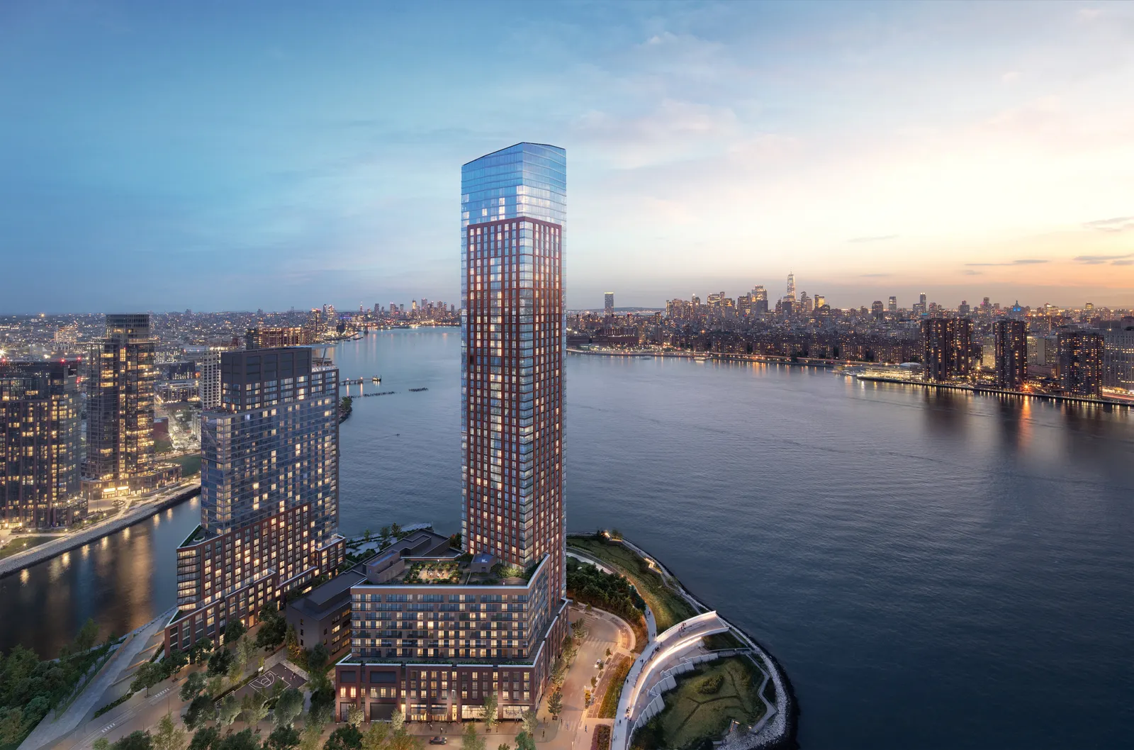 A set of tall buildings beside a river, with a city skyline on the other side.