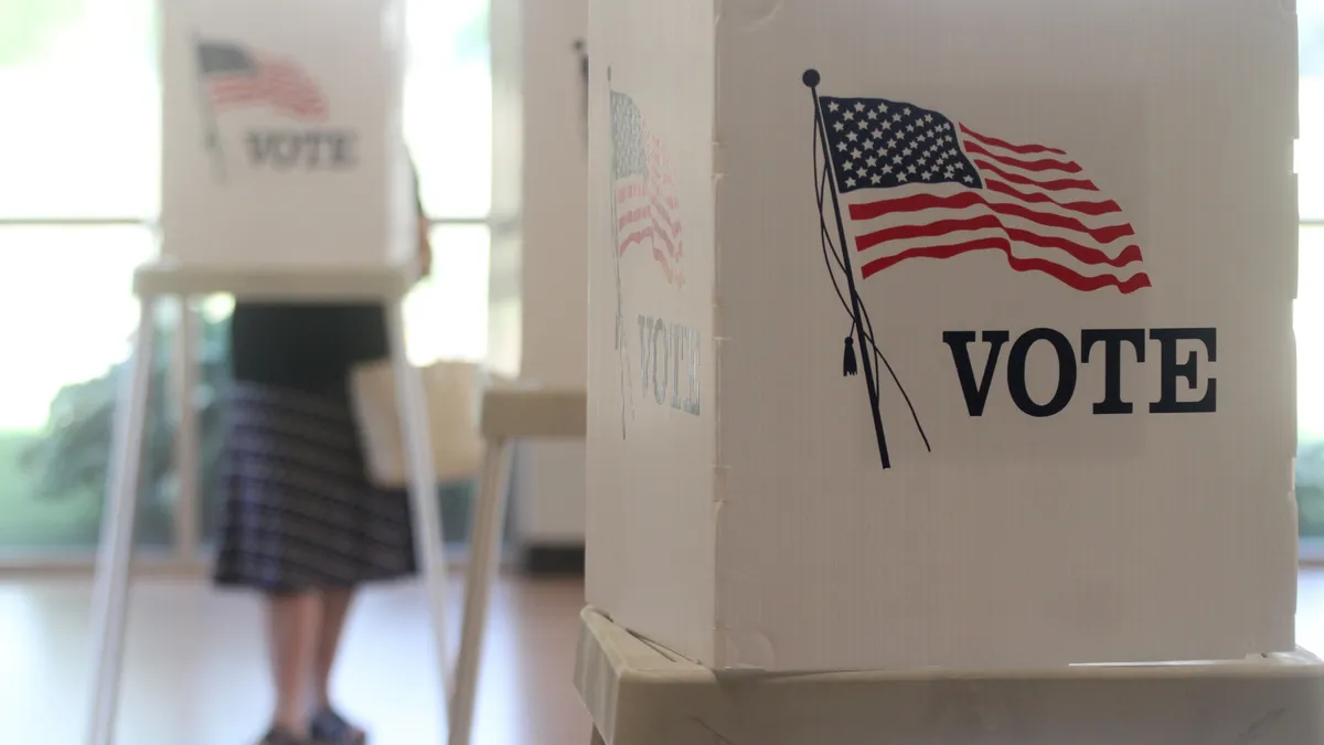 A series of voting booths in a brightly lit room.