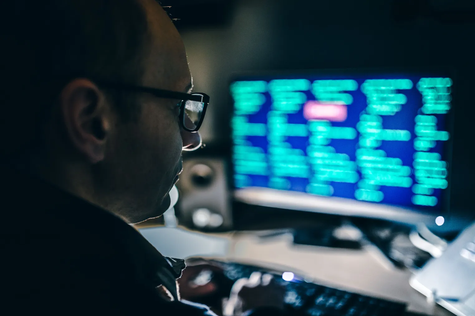 A man looks at lines of code depicted on a computer screen