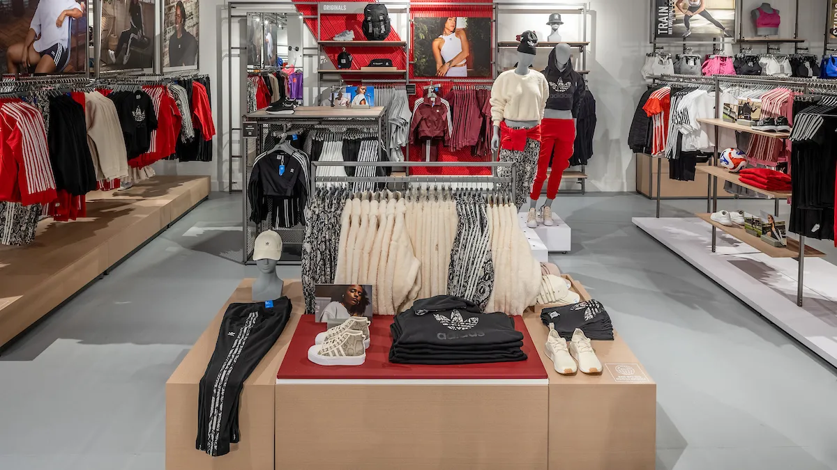 Interior shot of the Adidas store in the Bronx. Clothes are on racks on the perimeter of the store and merchandise on tables in the center.