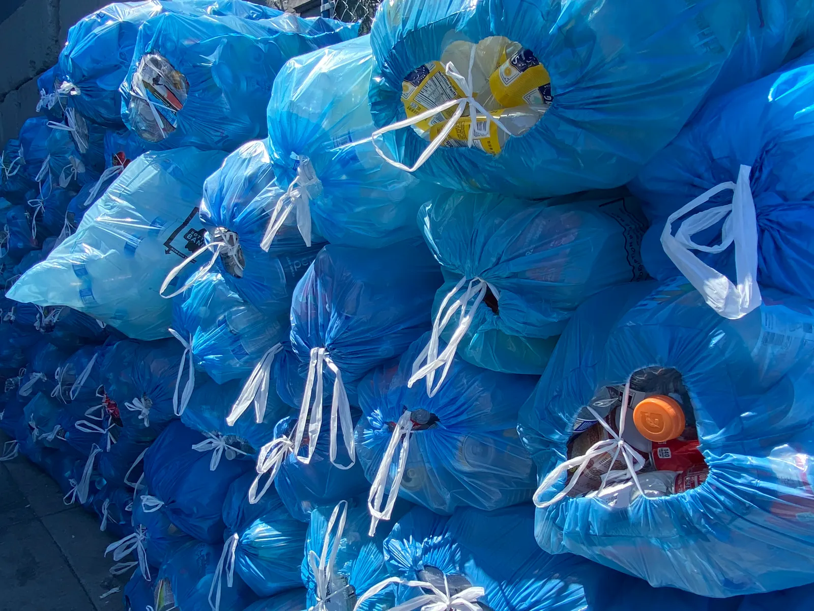 stacks of blue bags filled with recycled beverage containers