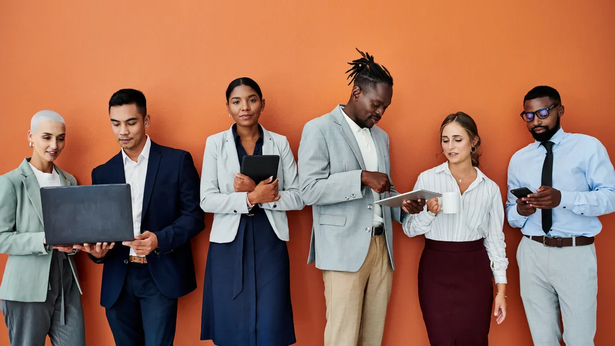 Portrait of a  business people standing alongside her colleagues against an orange background