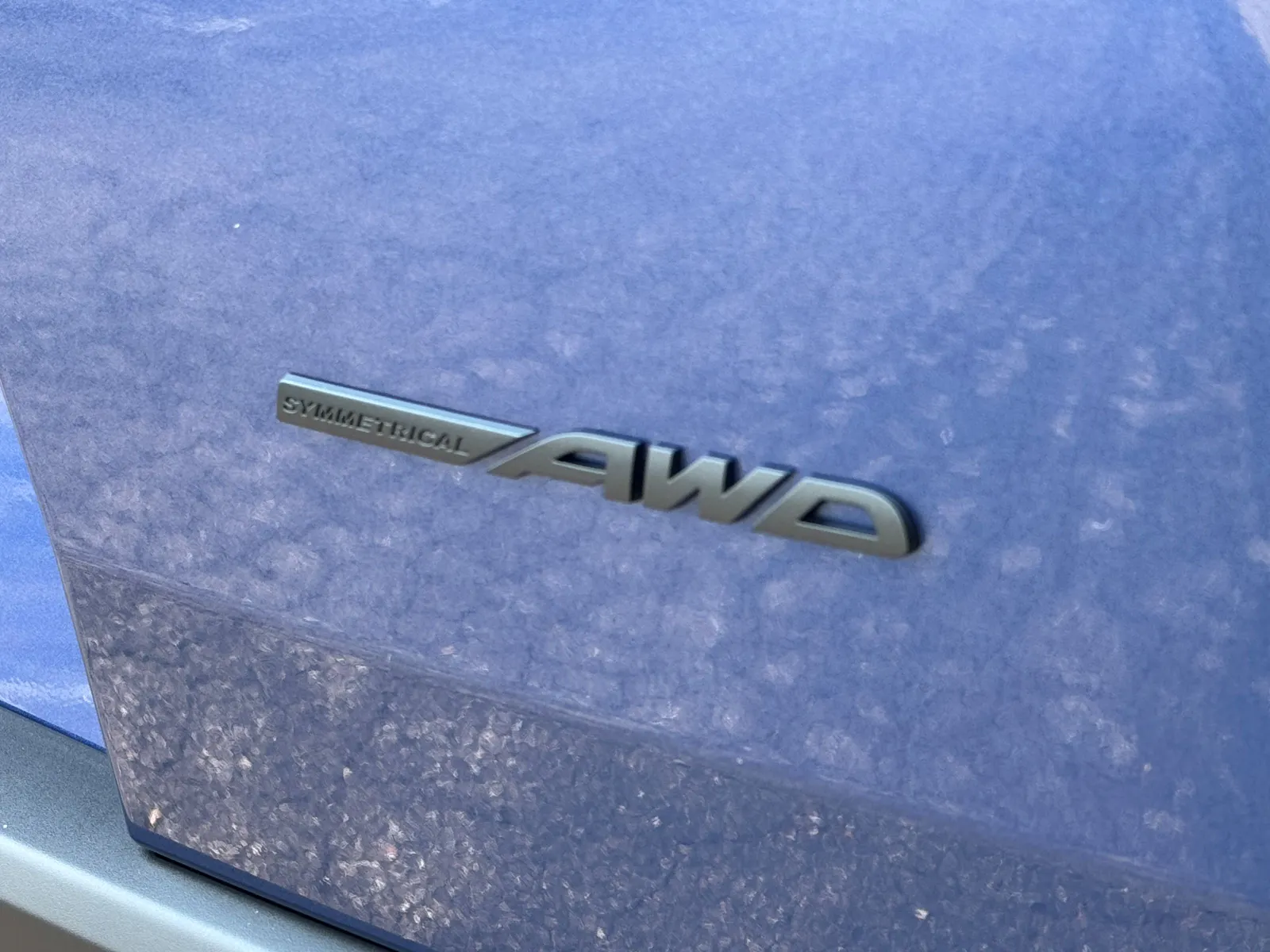 Signage saying "Symmetrical AWD" is seen displayed on a blue Subaru Trailseeker.
