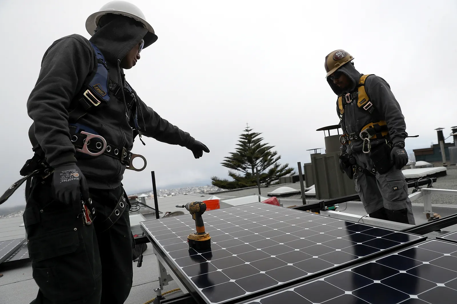 Luminalt solar installers Pam Quan and Walter Morales install solar panels on the roof of a home in San Francisco, California.