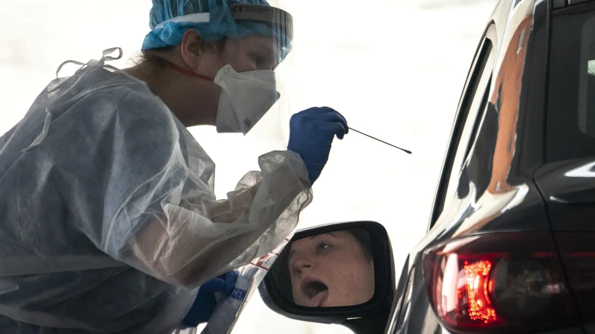 A man receiving a Covid test through his car window.