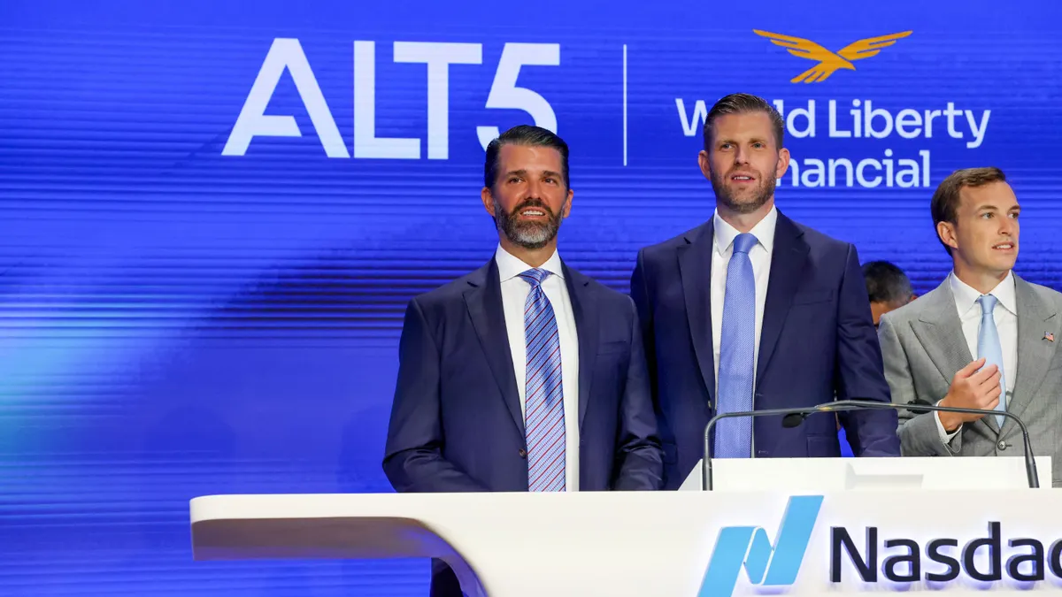 Two men in blue suits standing behind a podium and looking out to the left.