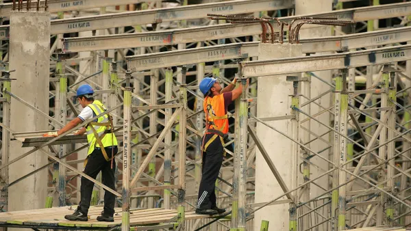 Construction workers work on a shopping center amid scaffolding.