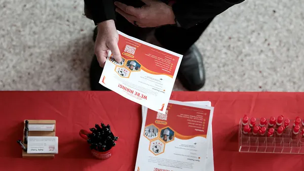 an overhead shot of a hiring booth with a man in business attire collects a flyer