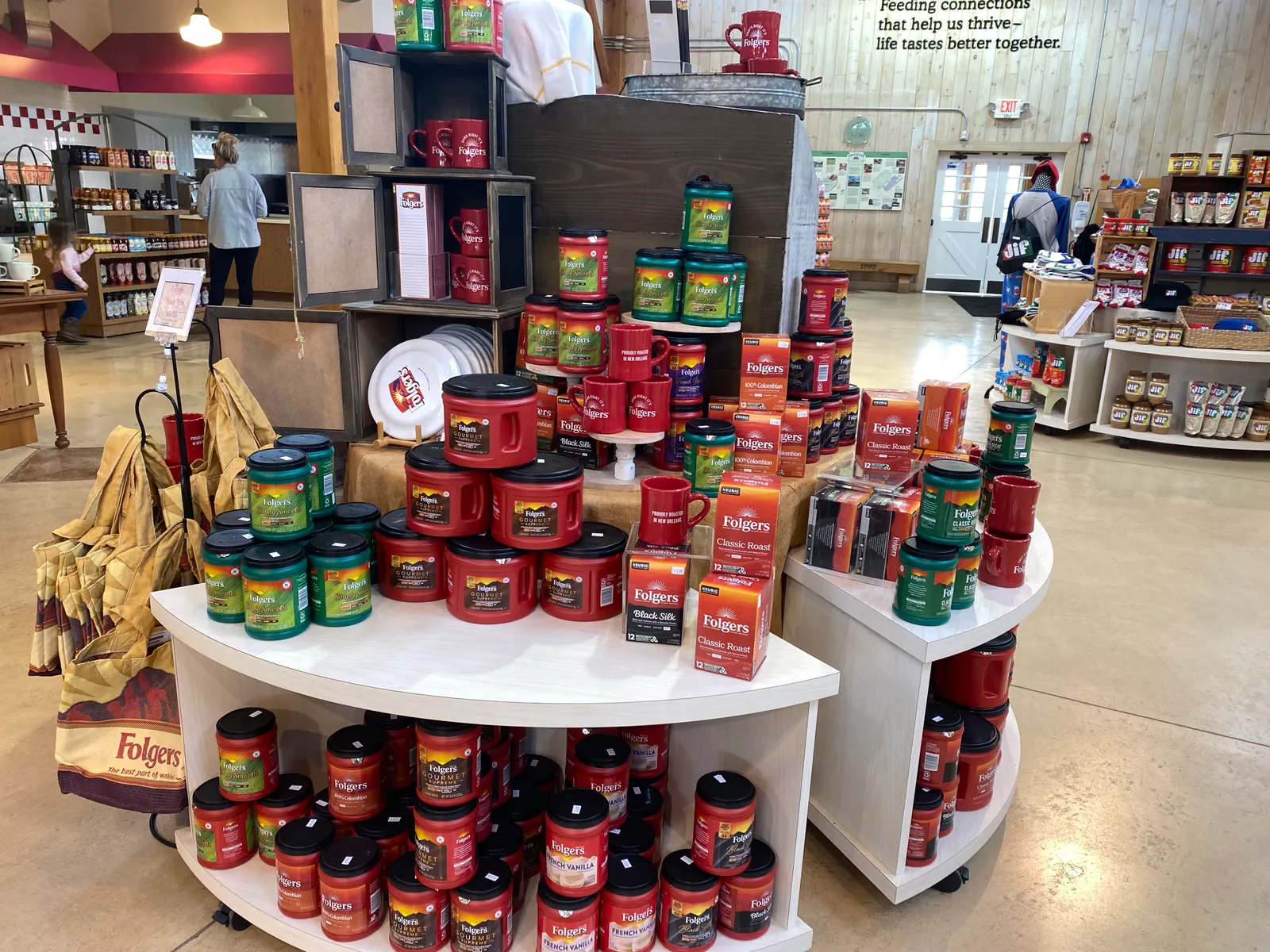Two white quarter-circle-shaped display tables featuring cans and containers of Folgers coffee in a store.