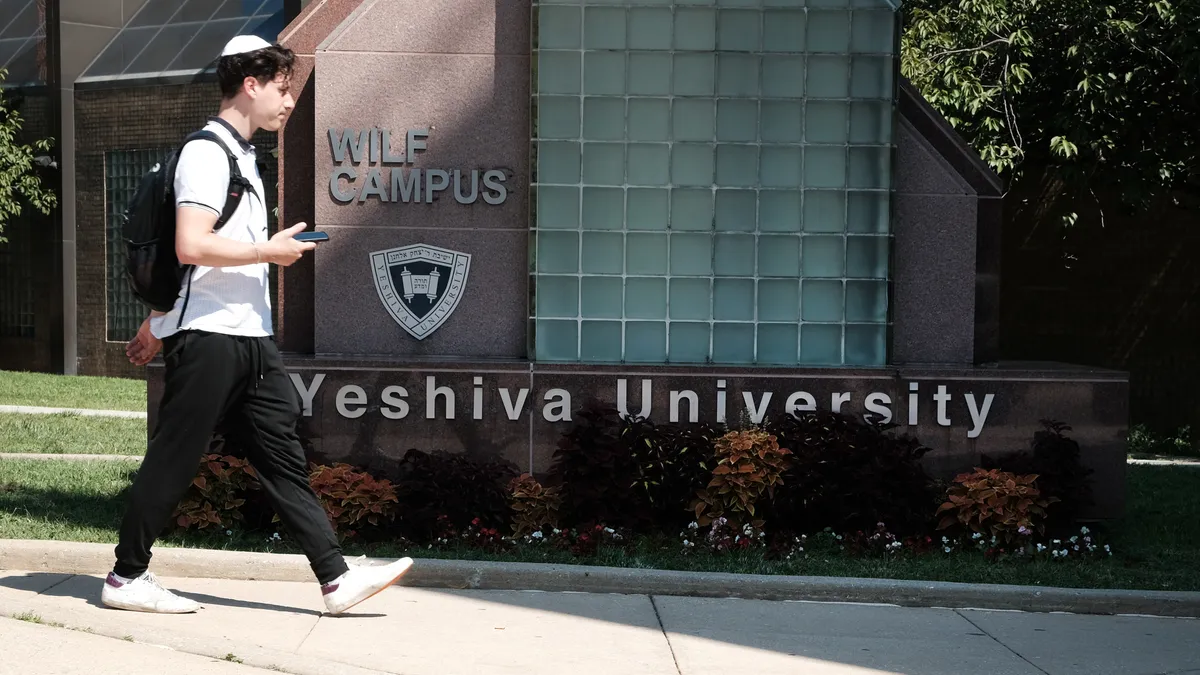 A person walks by a Yeshiva University sign.