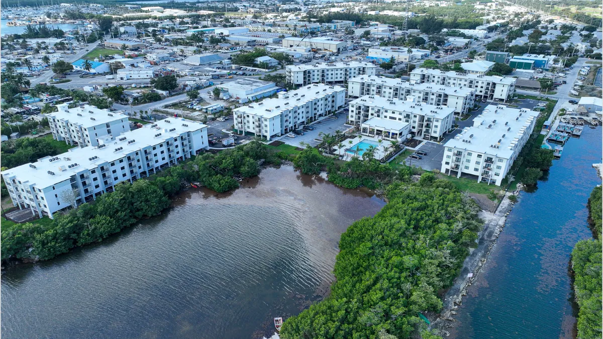 A set of white apartment buildings near a waterfront.