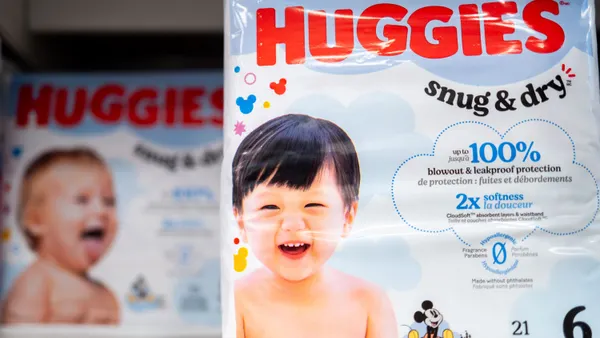 Packages of diapers are displayed on a store shelf. The packages read "Huggies Snug & Dry."
