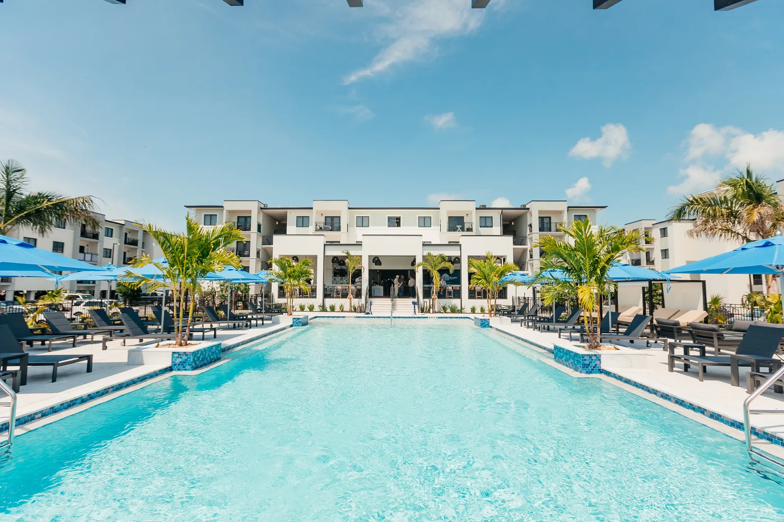 A pool with a large, white building at the far end.